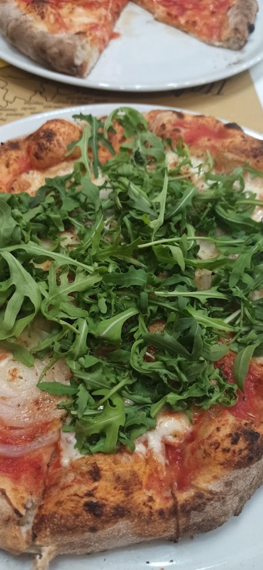 Una pizza con rucola e cipolla servita al tavolo