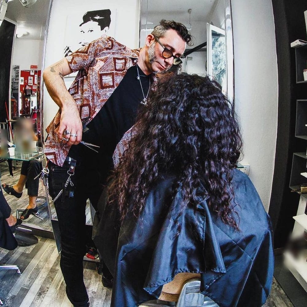 In salone: il taglio su lunghi capelli ricci, la cliente di spalle