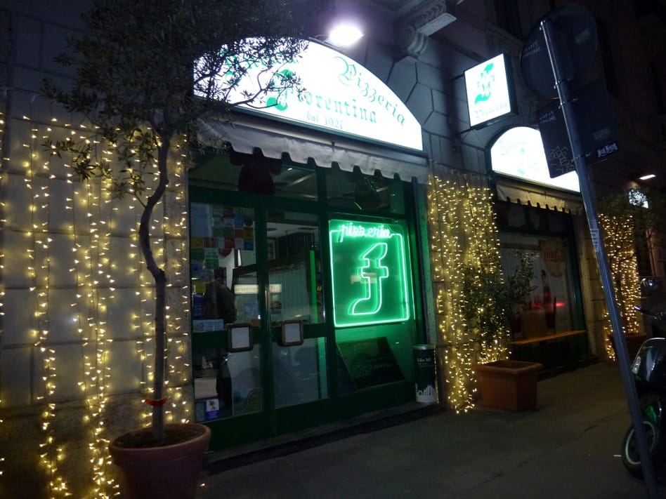 Facciata della pizzeria di notte, insegna verde al neon e luci