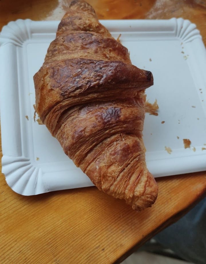 Un cornetto dorato sul vassoio di carta, sulla mensola di legno.