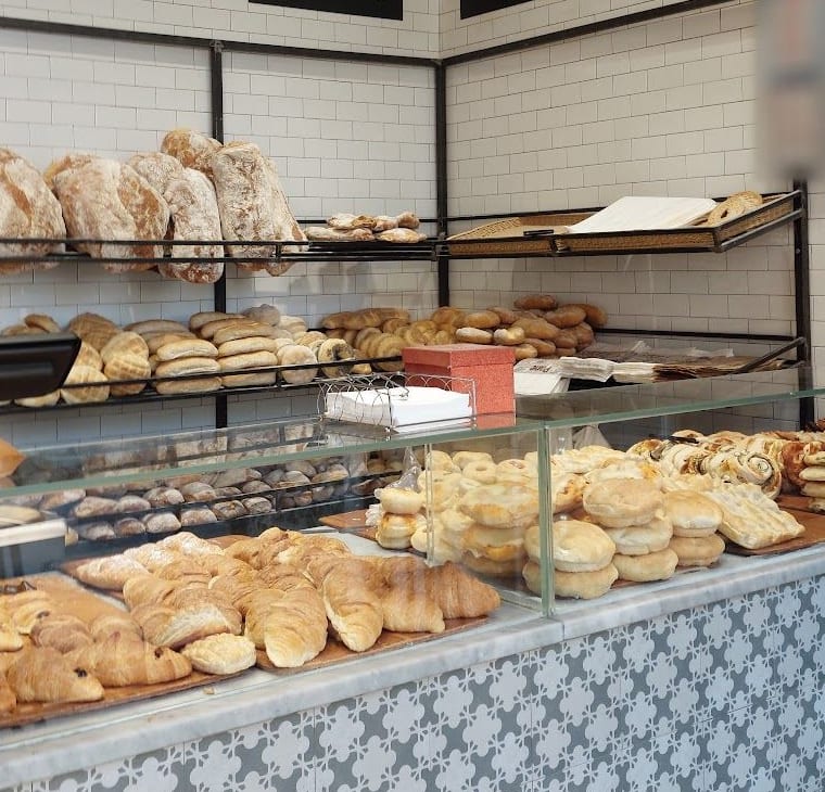 Le mensole di ferro sulle piastrelle bianche coi pani grandi e i panini, e il banco di marmo con le brioche.