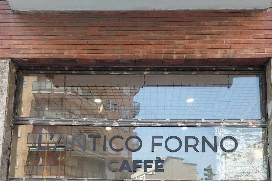 La vetrina in Via Ettore Ponti: la fascia di mattoni e le lettere in rilievo «L'Antico Forno Caffè» sul vetro.