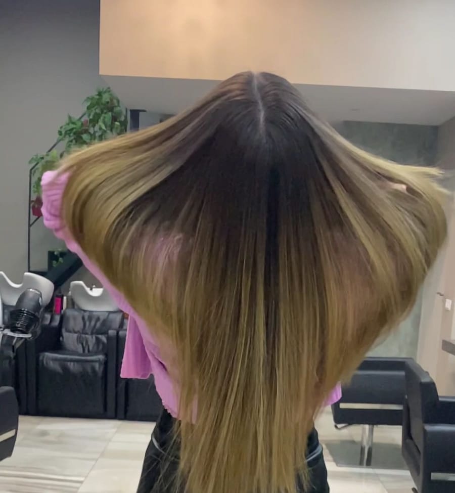 Capelli lunghi di spalle, castani alla radice e schiariti verso le punte, aperti con le mani