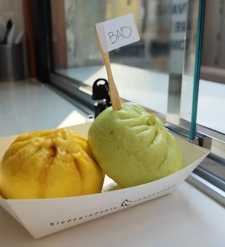 Un bao giallo e uno verde nella vaschetta sul banco della finestra, con la bandierina «BAO» scritta a mano.