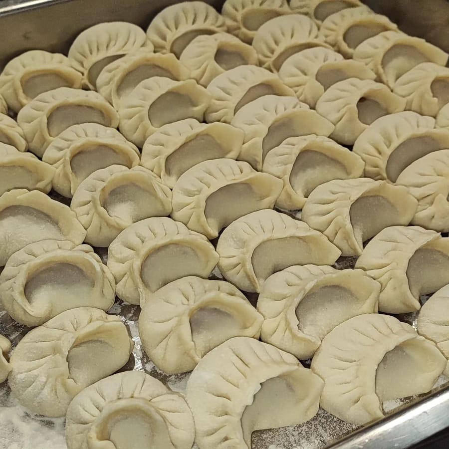 I ravioli crudi, pieghettati, in file sulla teglia infarinata.