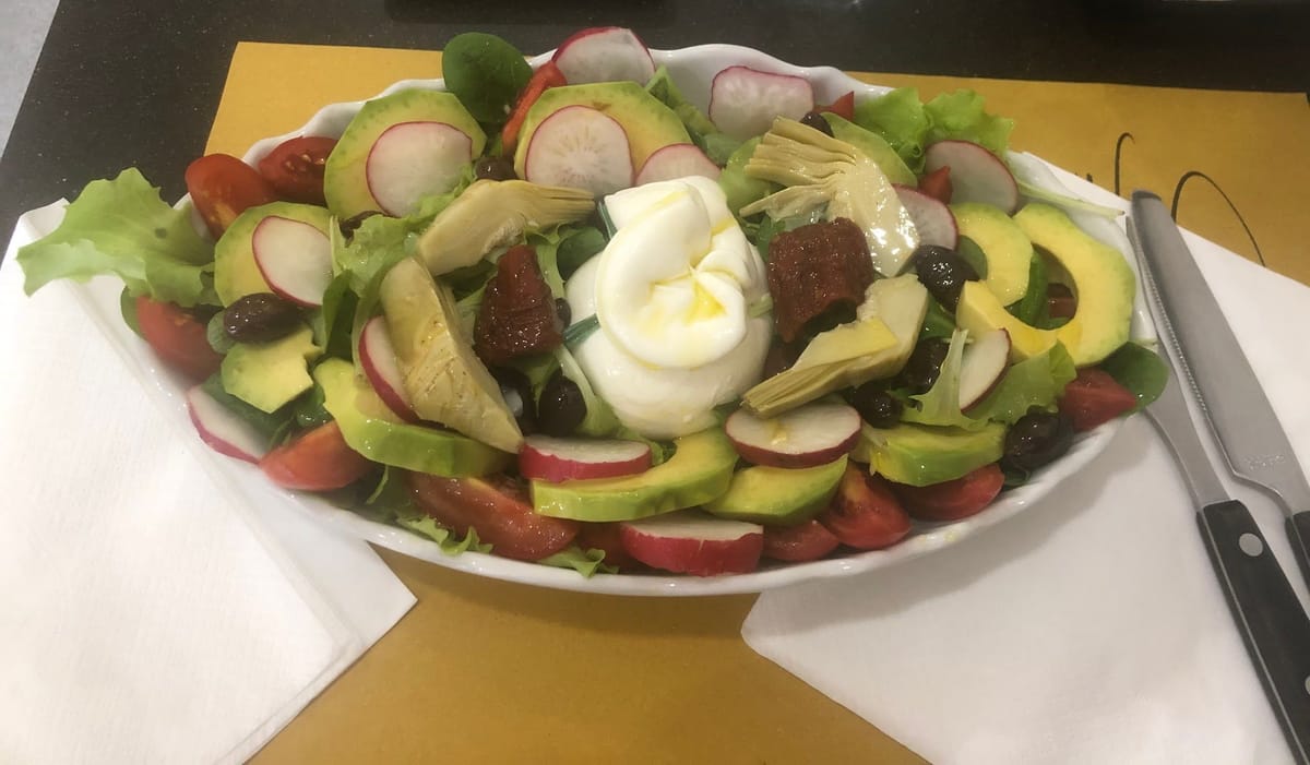 Un'insalata del pranzo: burrata, avocado, ravanelli, carciofi e pomodori.