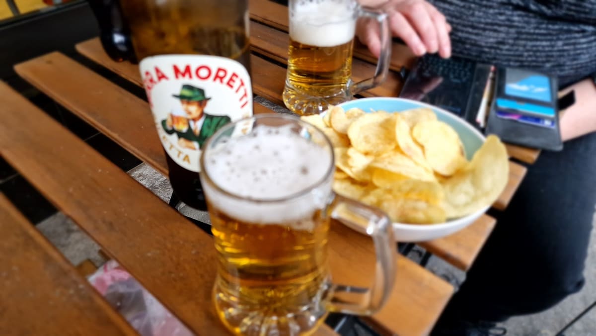 Due boccali di birra e una ciotola di patatine su un tavolino di legno