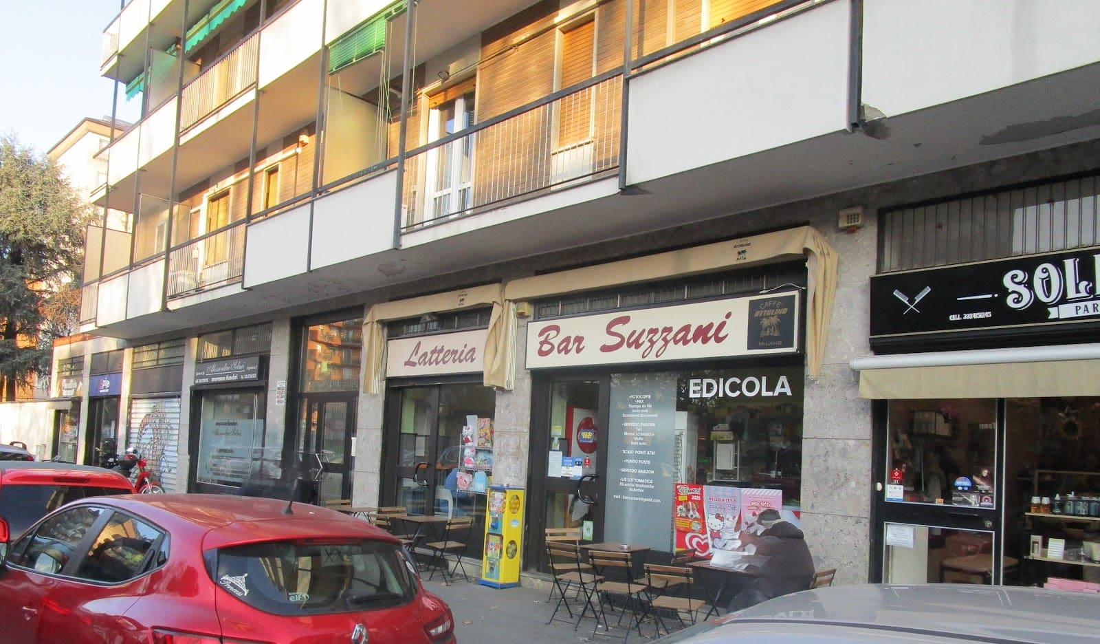 La facciata intera del bar sotto il palazzo, con le insegne Latteria, Bar Suzzani ed Edicola
