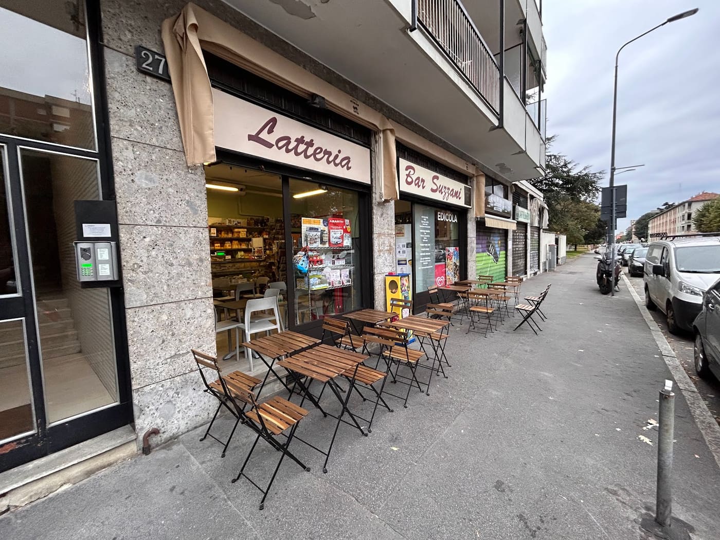 I tavolini di ferro e legno sul marciapiede davanti all'insegna Latteria