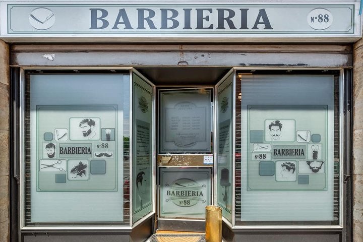 La vetrina di Barbieria 88 in via Monte Rotondo 3, con l'insegna BARBIERIA e il tondo N°88