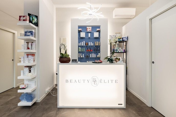La reception di Beauty Élite: bancone bianco retroilluminato e parete blu con i prodotti