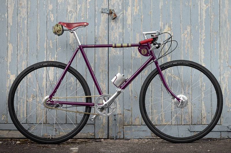 Bicicletta classica bordeaux appoggiata a una porta di legno azzurra