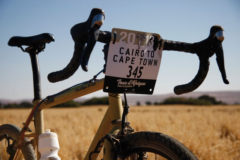 Bici da viaggio con targa Cairo to Cape Town in un campo di grano