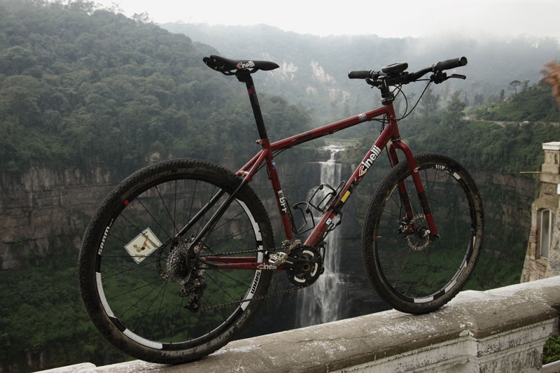 Mountain bike rossa davanti a un canyon con cascata