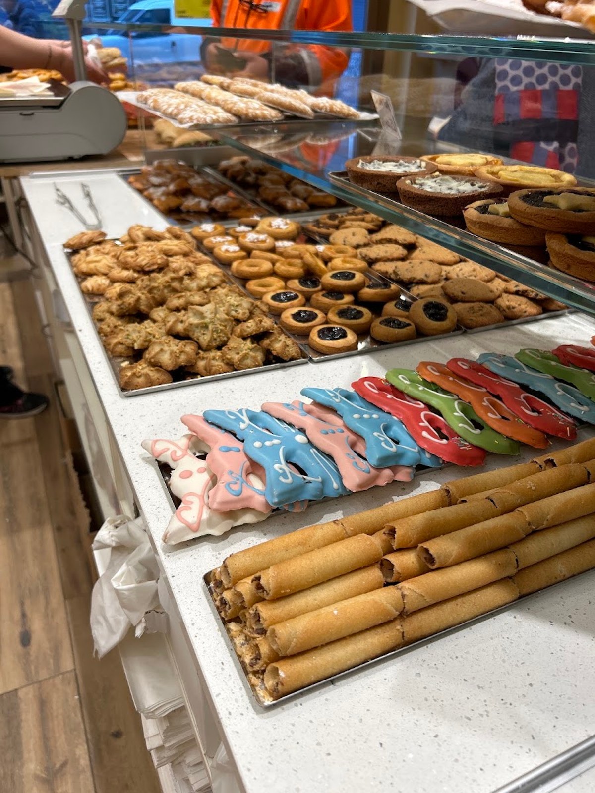 Vassoi di biscotti secchi, crostatine e dolcetti glassati colorati sul banco della pasticceria