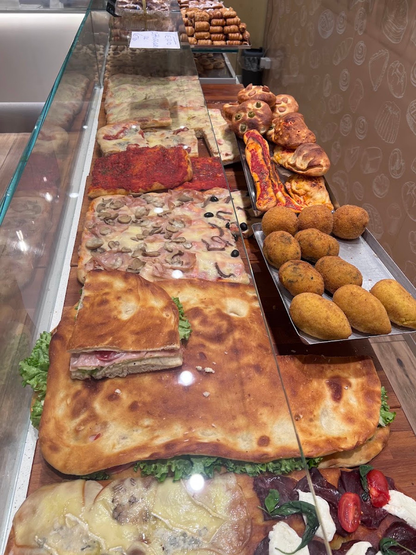 Il banco dei salati: pizza in teglia rossa e bianca, con funghi e prosciutto, panzerotti fritti e una focaccia farcita