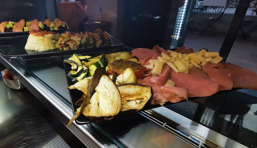Il banco del pranzo con le verdure grigliate, gli affettati e le torte salate.