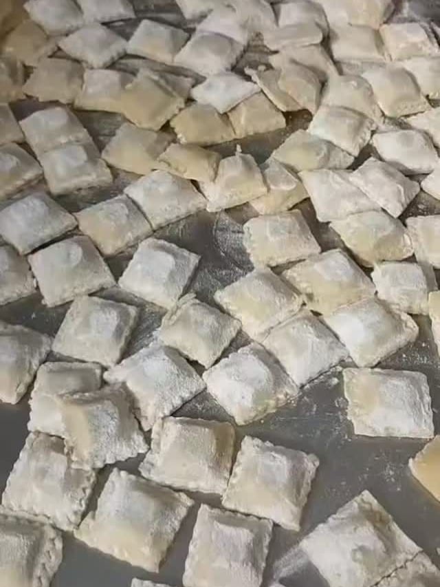 Ravioli freschi stesi sul piano infarinato.