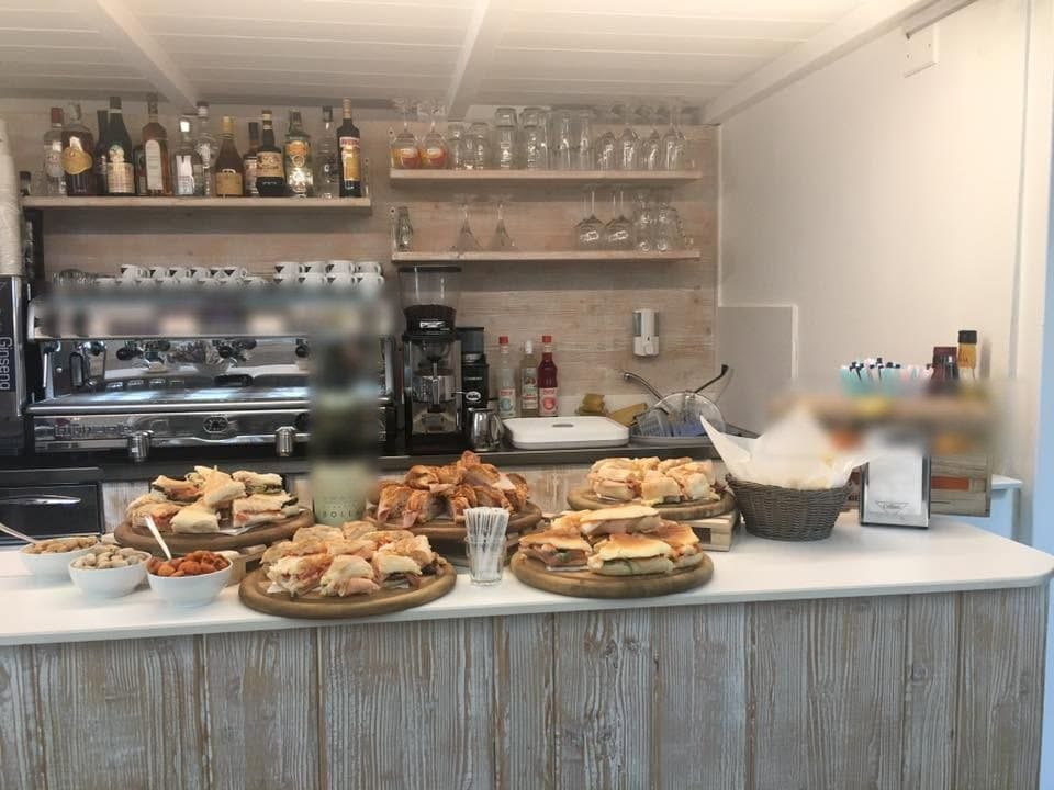 Il bancone in legno chiaro coi taglieri di tramezzini e focaccine, la macchina dell'espresso.