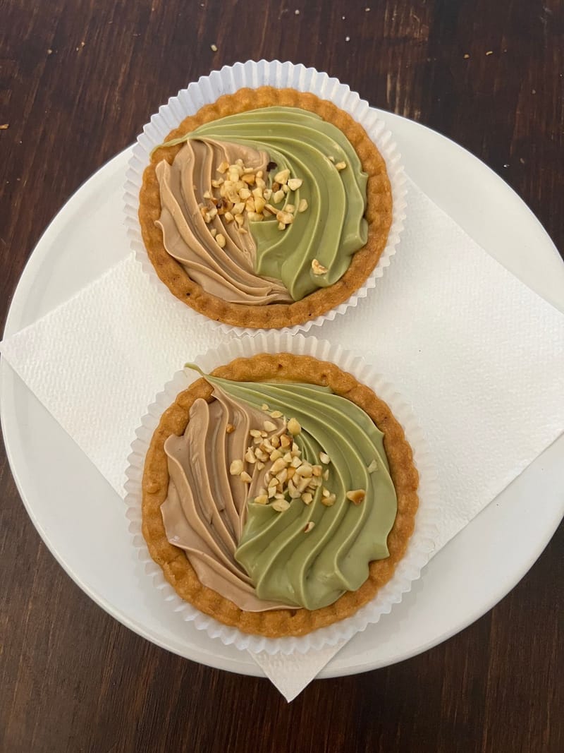 Due crostatine al pistacchio sul piatto.
