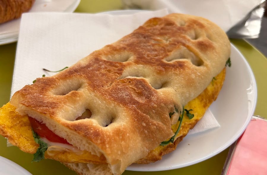 Una focaccia farcita sul piatto, sul tavolino verde.
