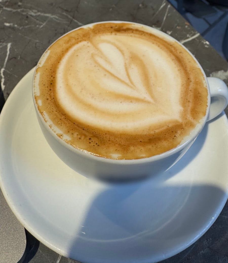 Un cappuccino col cuore di schiuma sul banco di marmo nero venato di bianco