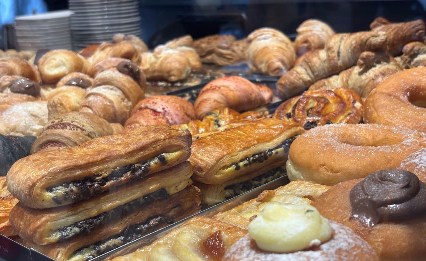 La vetrina delle brioche: croissant, pain au chocolat con le gocce di cioccolato, sfoglie, krapfen con la crema e la cioccolata, zucchero a velo