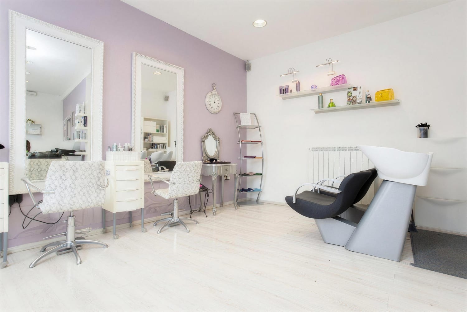 Interno del salone Calajò: pavimento bianco, parete lavanda, specchi con cornici e postazioni indipendenti