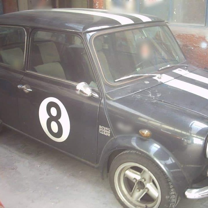 Una Mini scura con le strisce bianche e il numero 8 sulla portiera