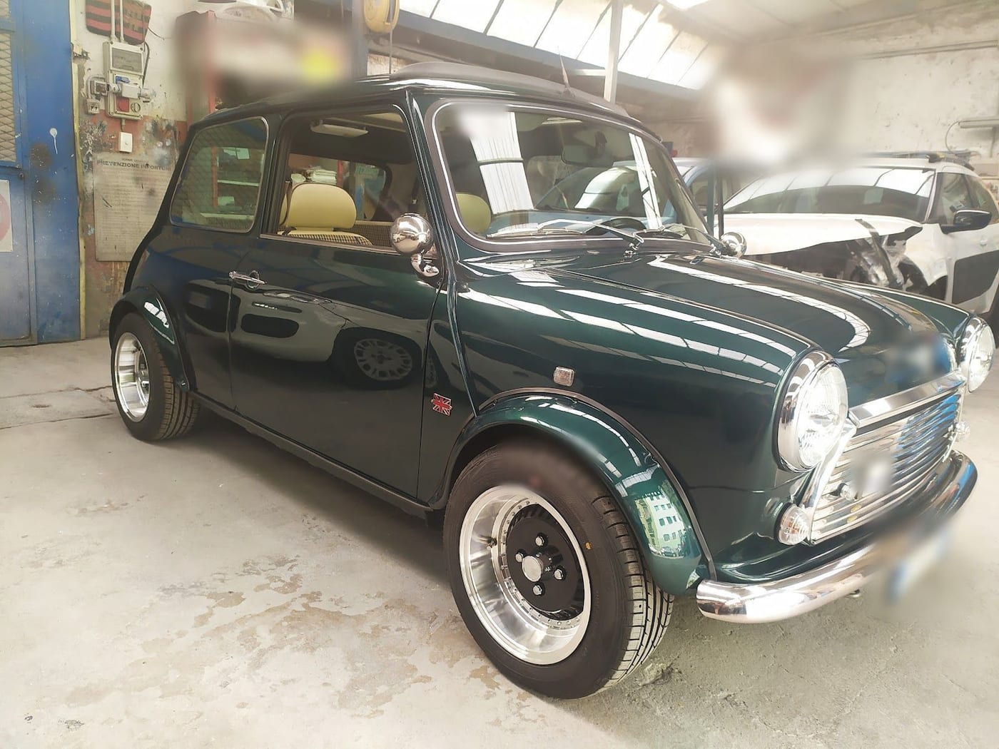 Una Mini verde inglese col tetto nero e i cerchi lucidi, in officina