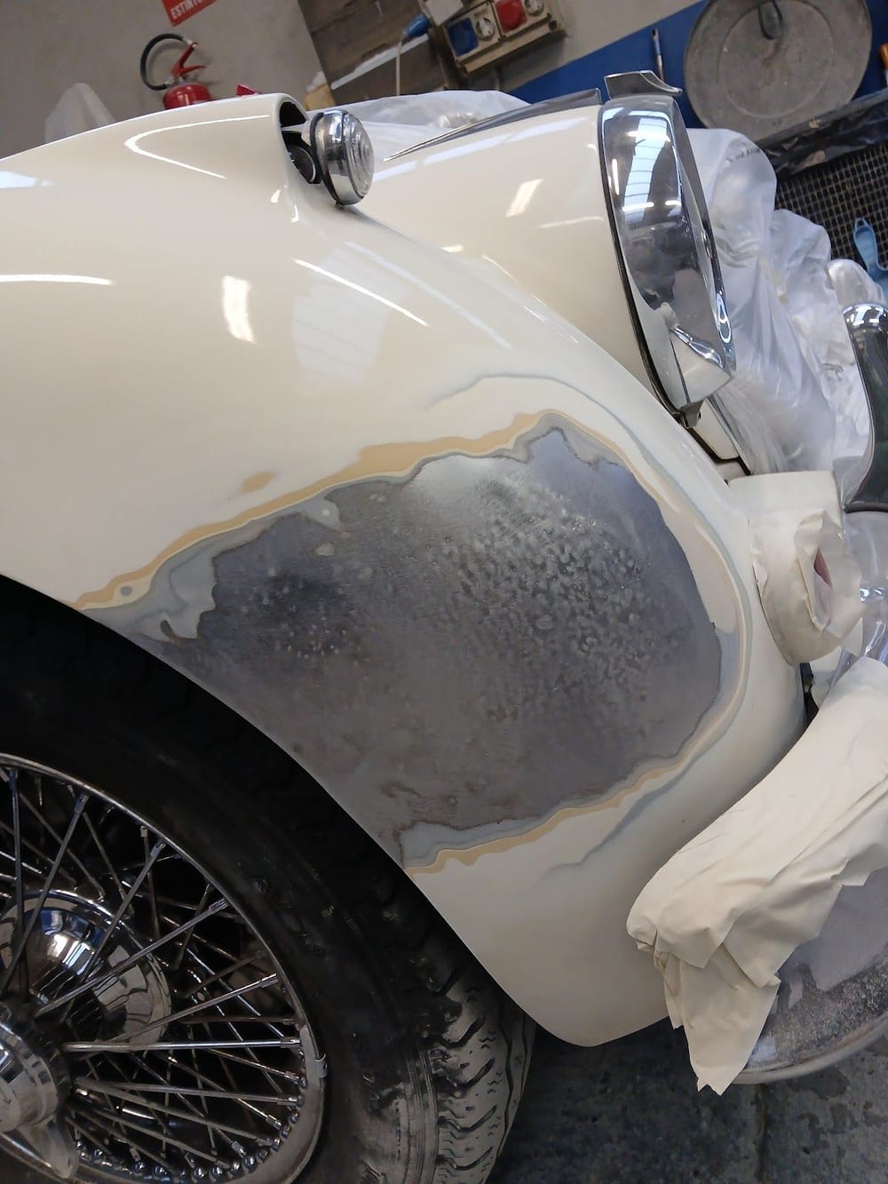 Il parafango crema di un'auto d'epoca con la lamiera a nudo e lo stucco