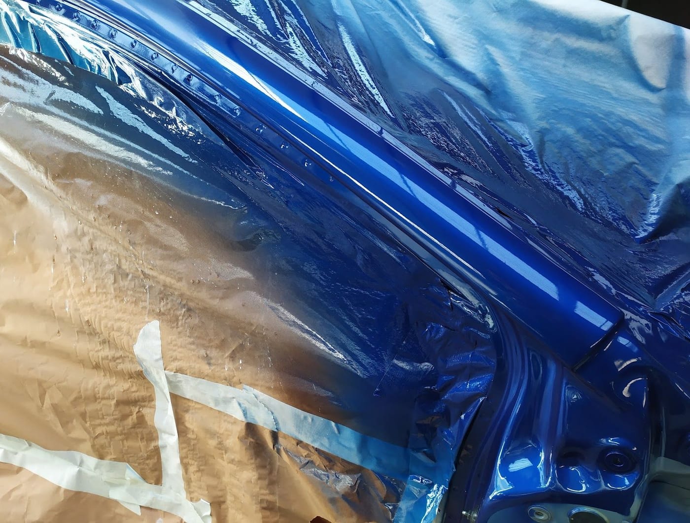 Una fiancata blu appena verniciata, col nastro e la carta intorno