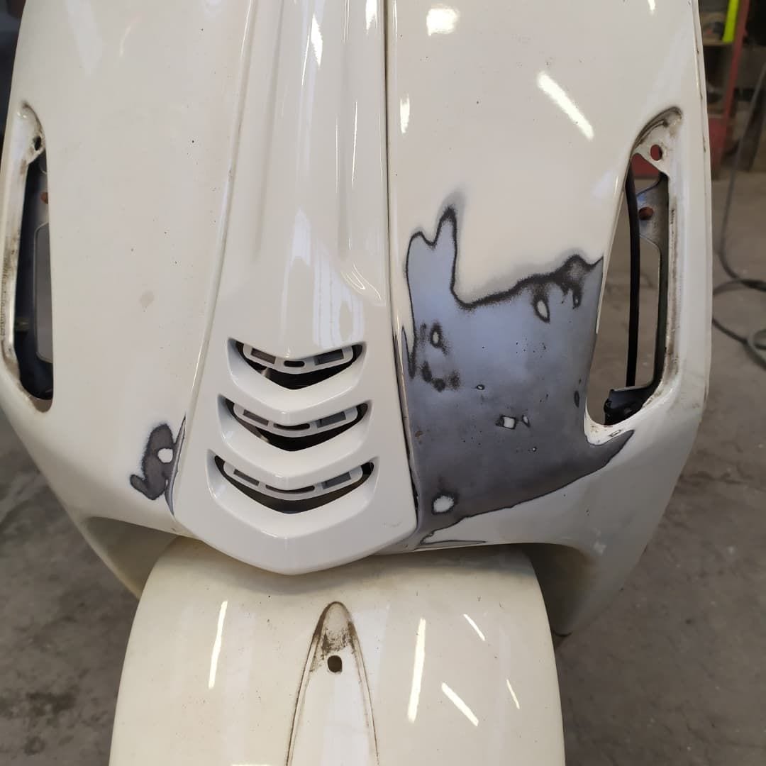 Lo scudo anteriore di una Vespa bianca, stuccato dove c'era il danno