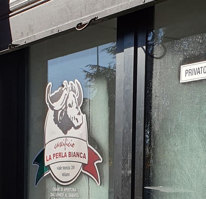 L'adesivo con il logo della bufala e la scritta La Perla Bianca sulla porta a vetri del negozio