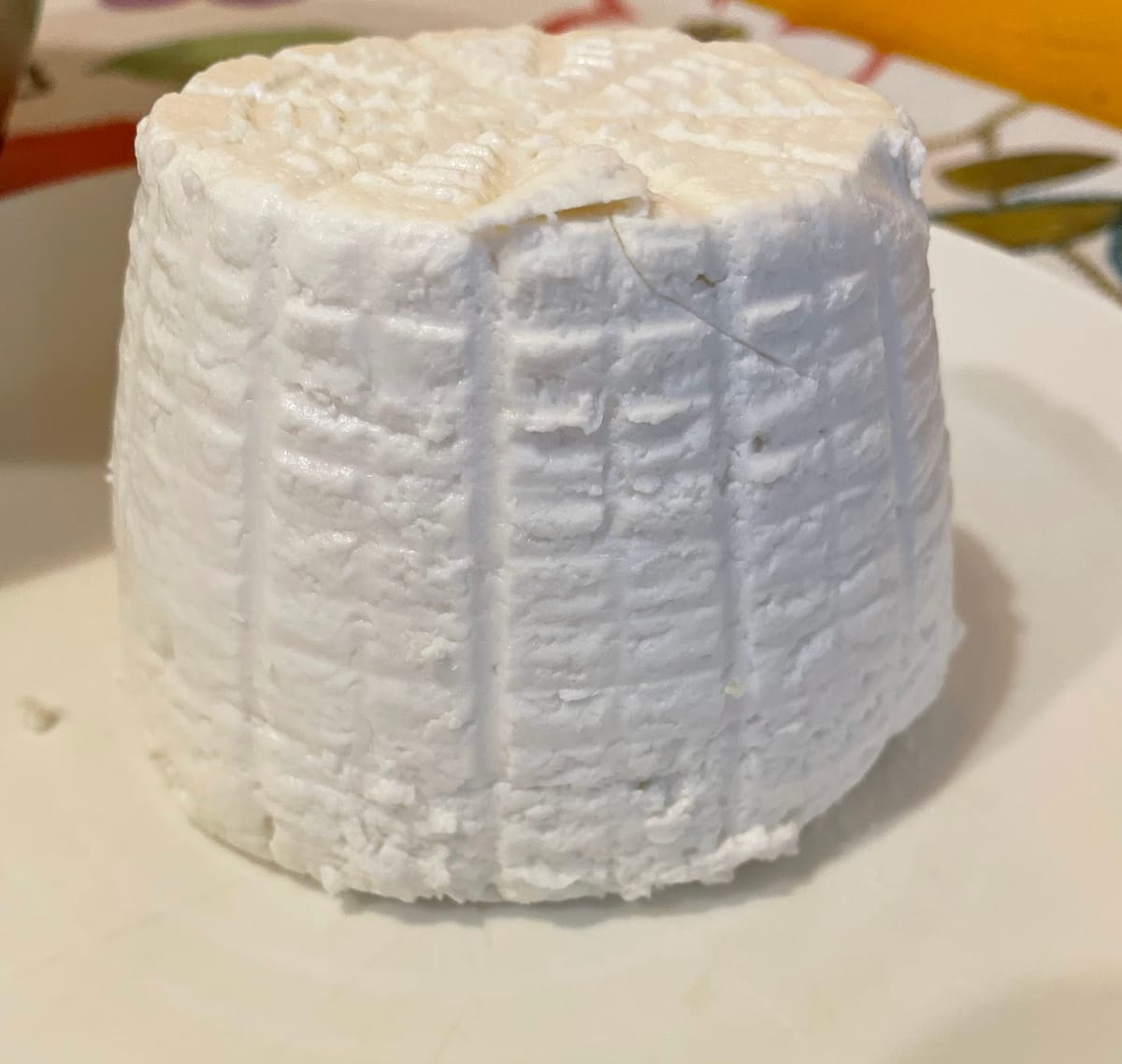 Una ricotta di fuscella appena sformata, con i segni del cestino, su un piatto