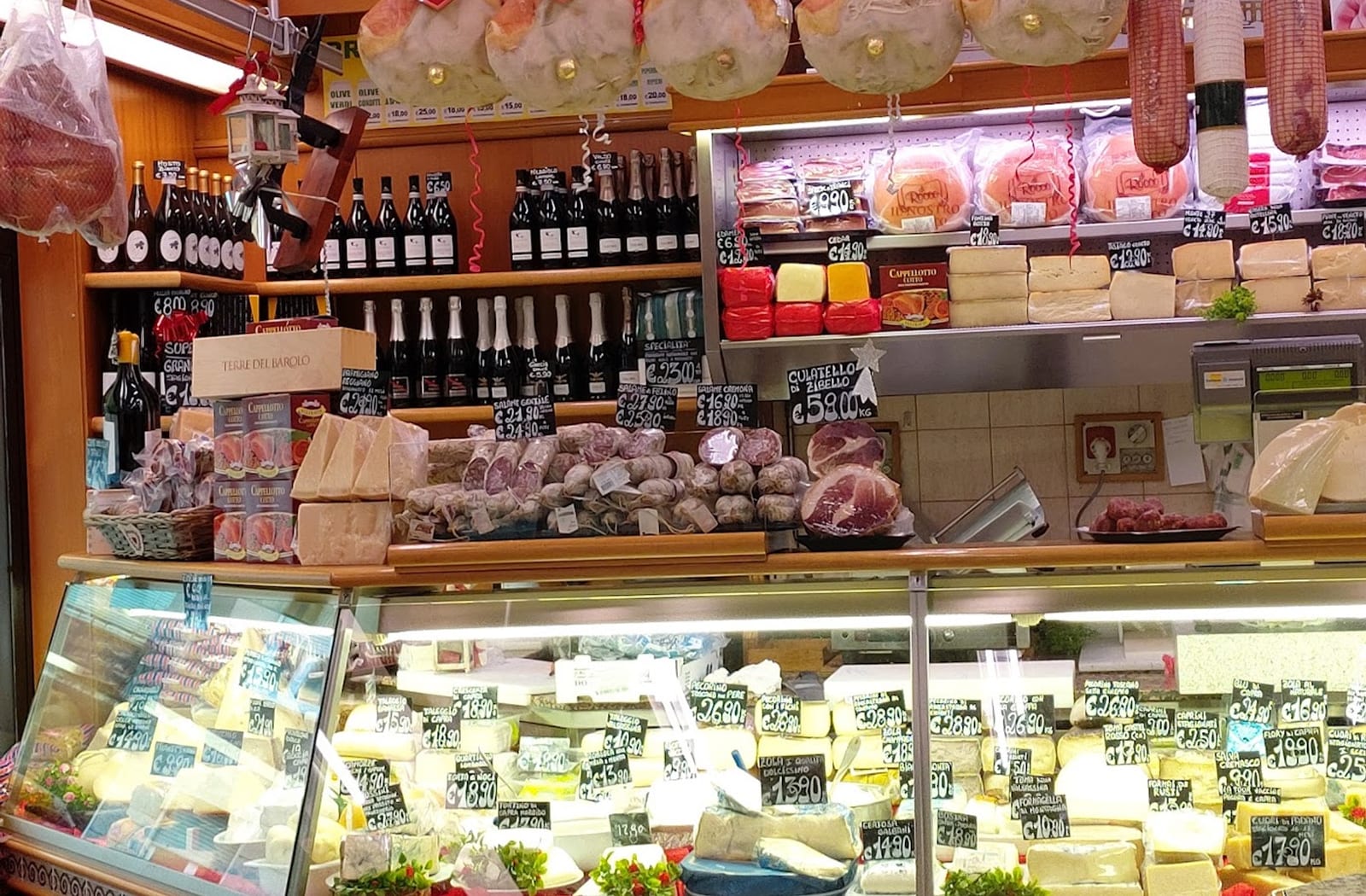 Il banco del Centro Carni Bovisa: salumi appesi, vini e la vetrina