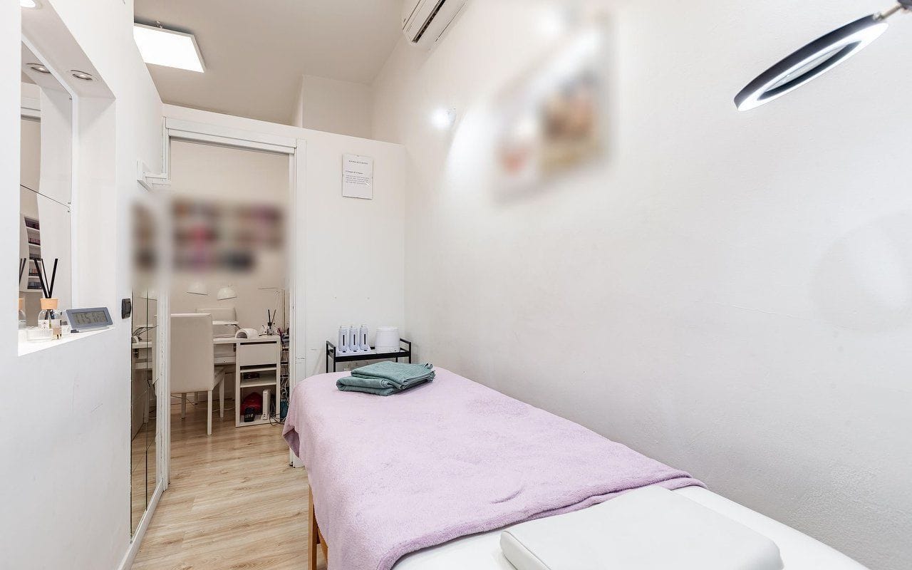 La cabina col lettino e il telo lilla, gli asciugamani piegati e la lampada ad anello