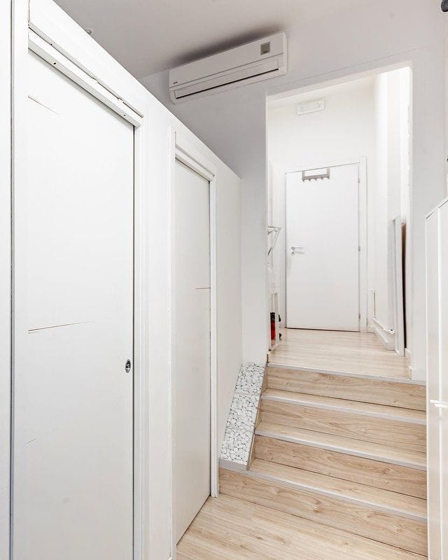 Il corridoio con le porte bianche scorrevoli e la scala di legno chiaro