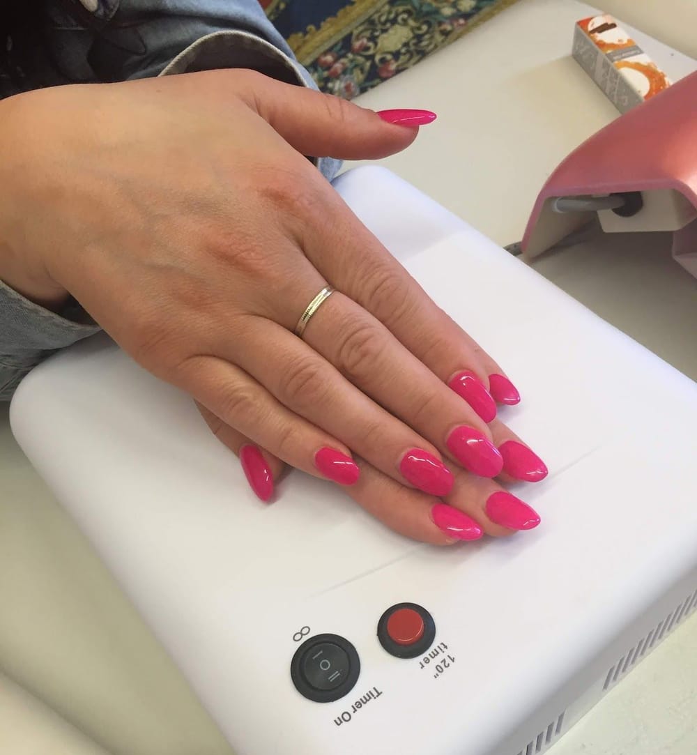 Unghie fucsia a mandorla sulla lampada UV bianca