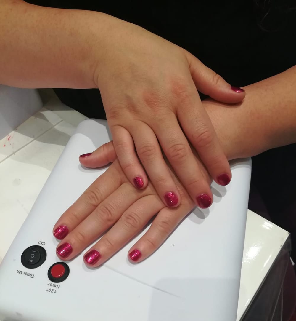 Unghie corte rosso glitter sulla lampada UV bianca