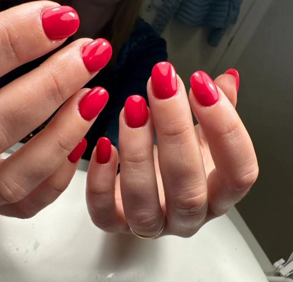 Unghie tonde rosso pieno, la mano sopra il poggiamani bianco