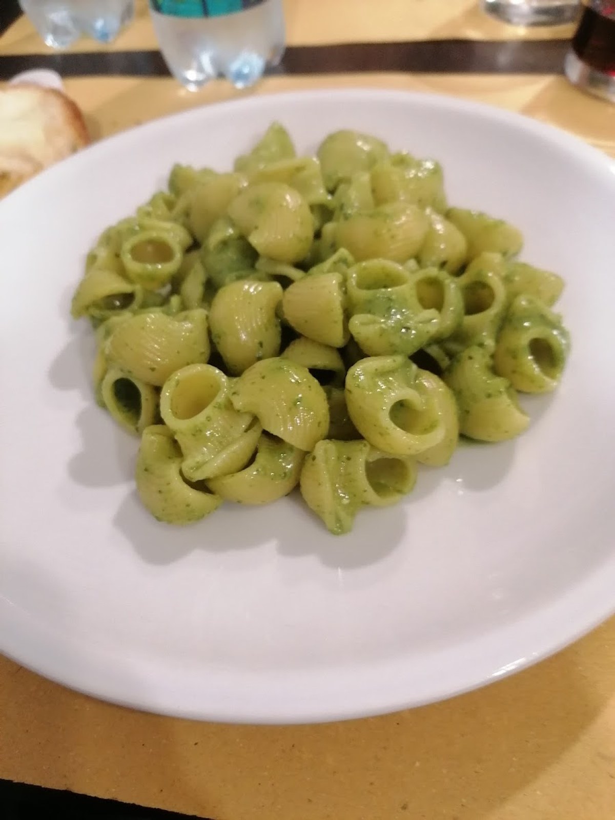Un piatto di pasta corta condita con pesto verde