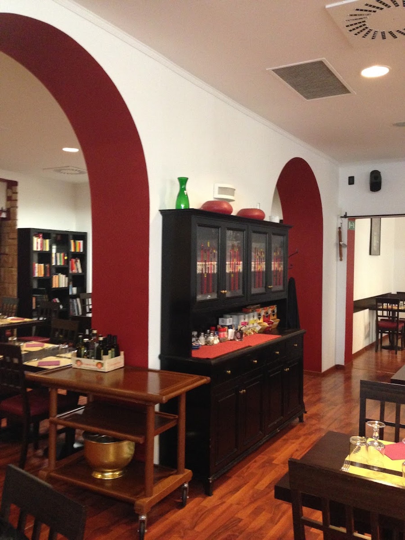 La sala con gli archi dipinti di rosso e la credenza nera vetrata