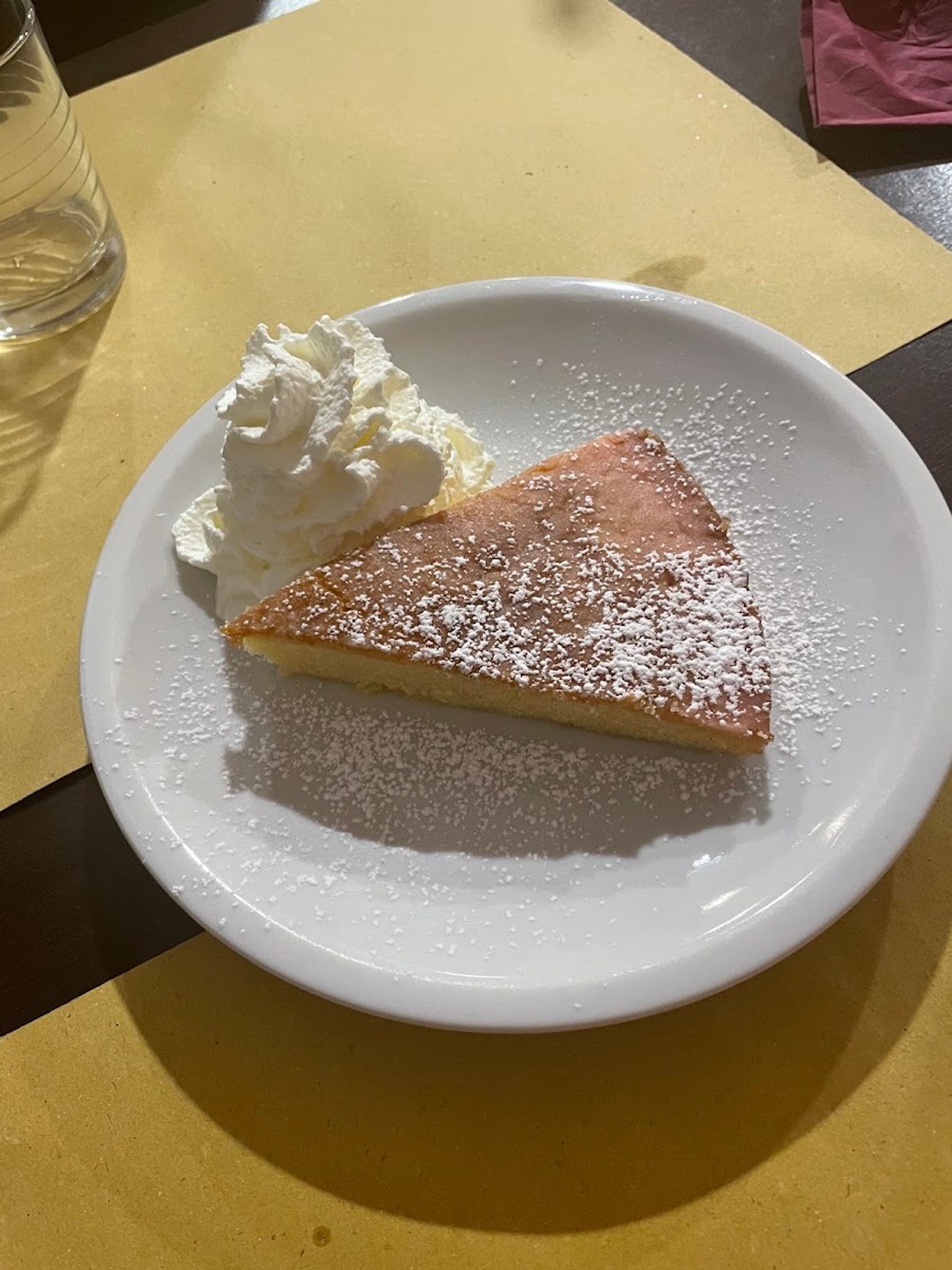 Una fetta di torta della casa spolverata di zucchero a velo, servita con la panna