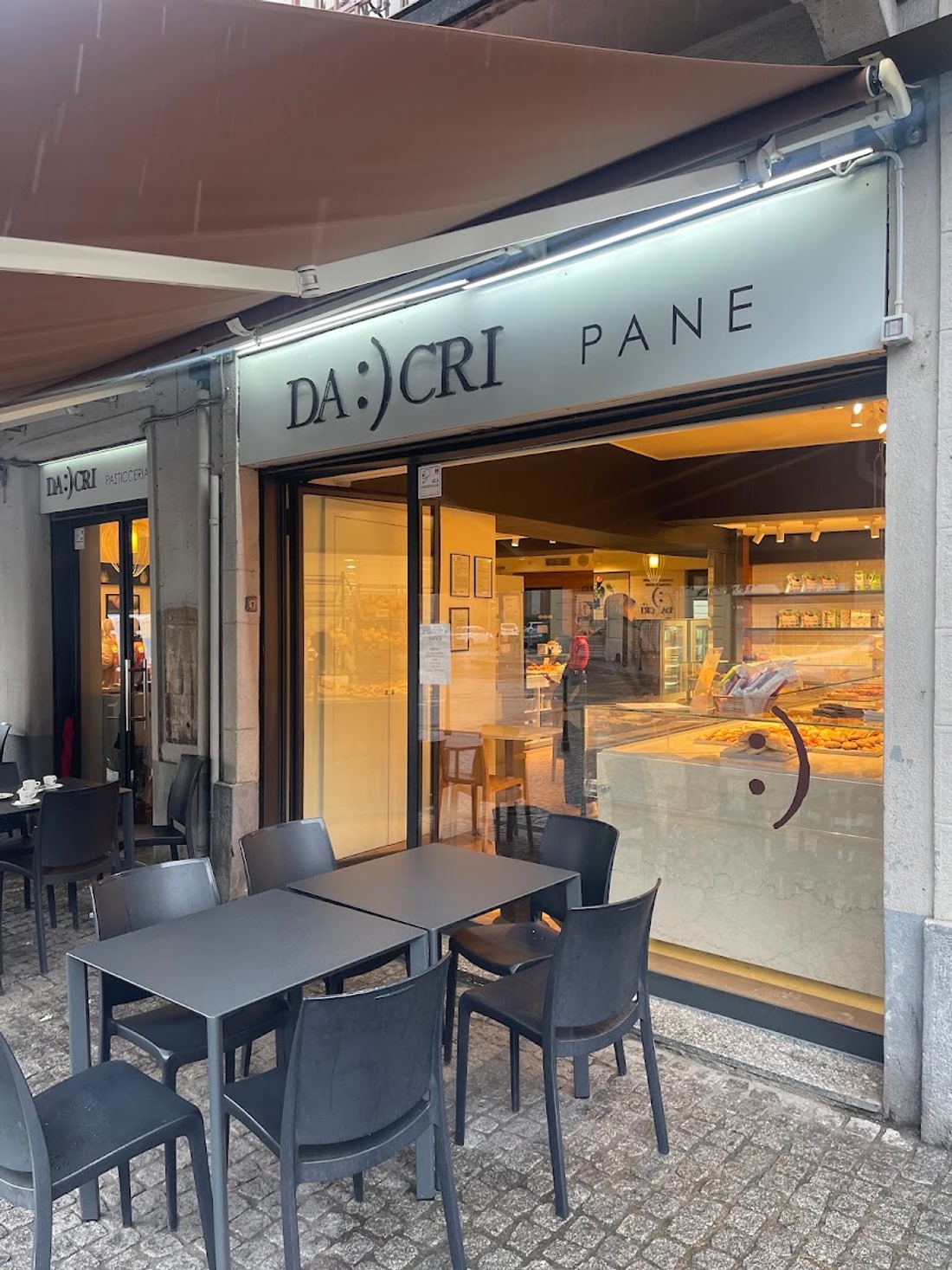 La facciata su Piazza Dergano: due vetrine affiancate, una PANE e una PASTICCERIA, con i tavolini fuori