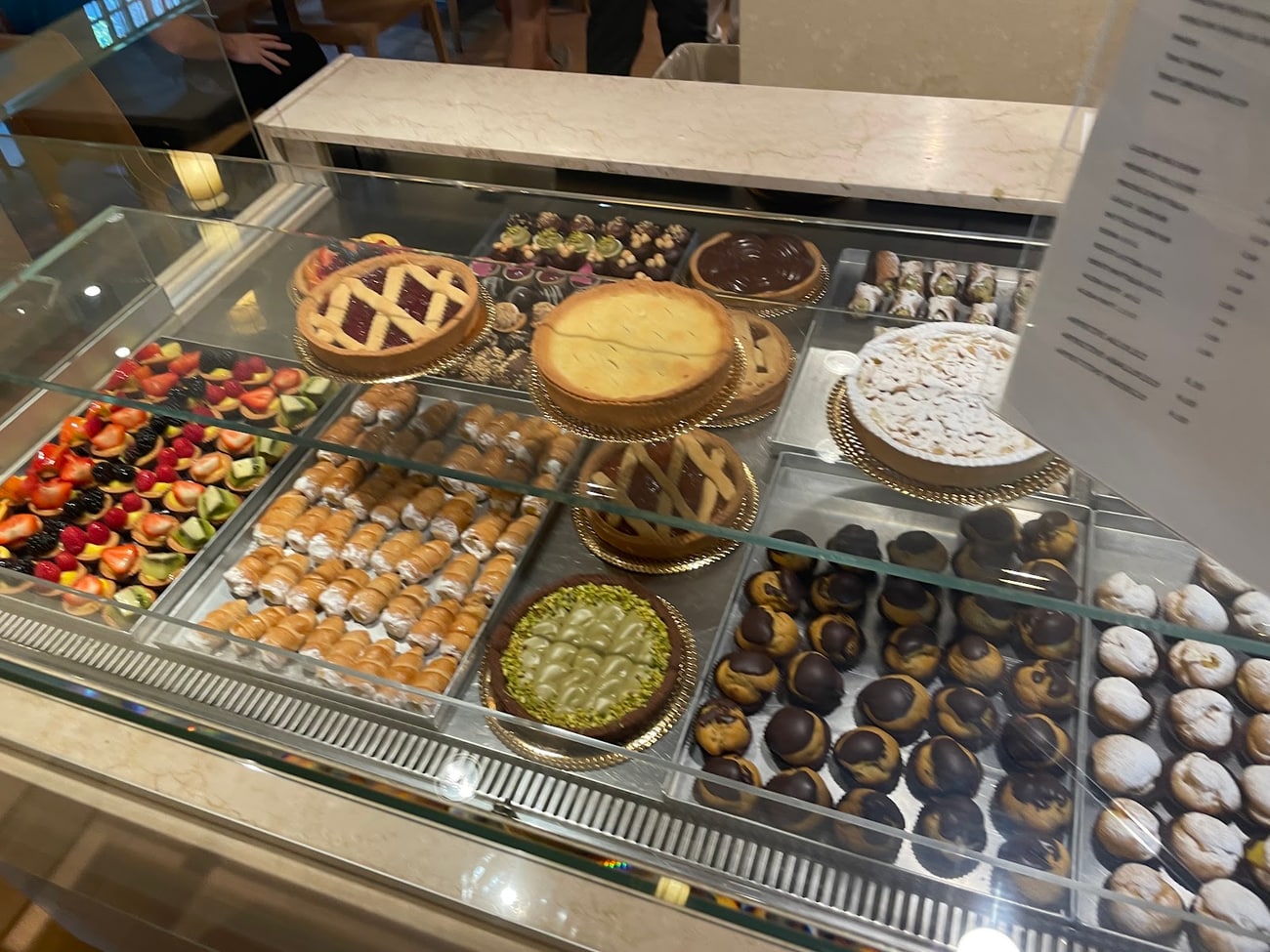Il banco della pasticceria con crostate, cannoncini, bignè e tartellette di frutta