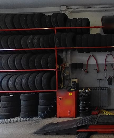 Dentro l'officina: le rastrelliere rosse piene di gomme, la smontagomme rossa, i cavalletti per le moto appesi al muro.