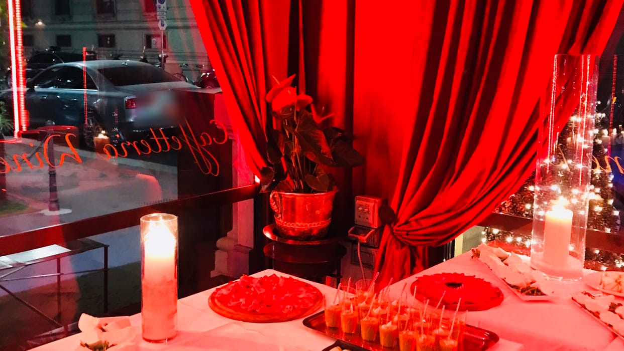 Le tende di velluto rosso, le candele e un buffet apparecchiato alla vetrina, di sera.