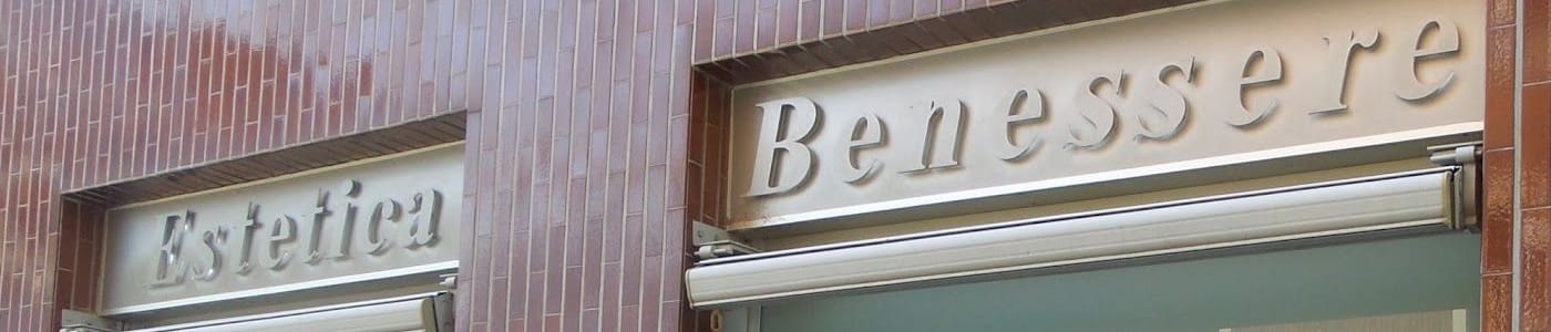 La facciata: le lettere d'acciaio in corsivo, Estetica e Benessere, sulle piastrelle marroni lucide.