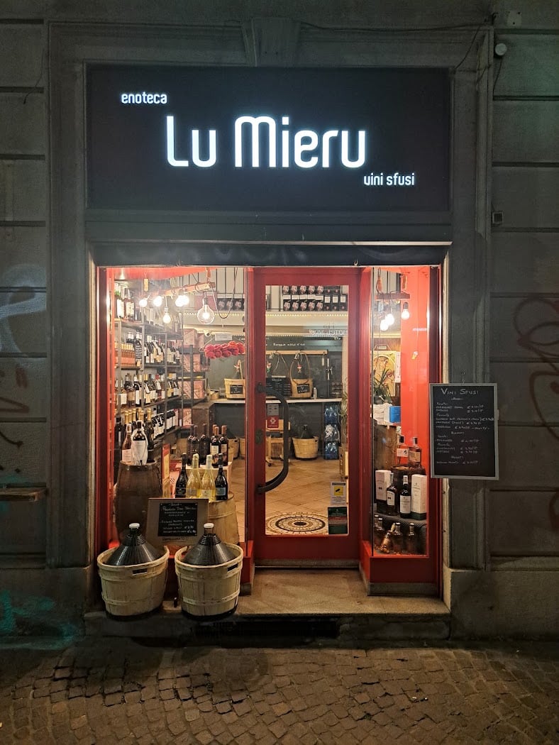 La vetrina dell'enoteca Lu Mieru con le insegne e le damigiane